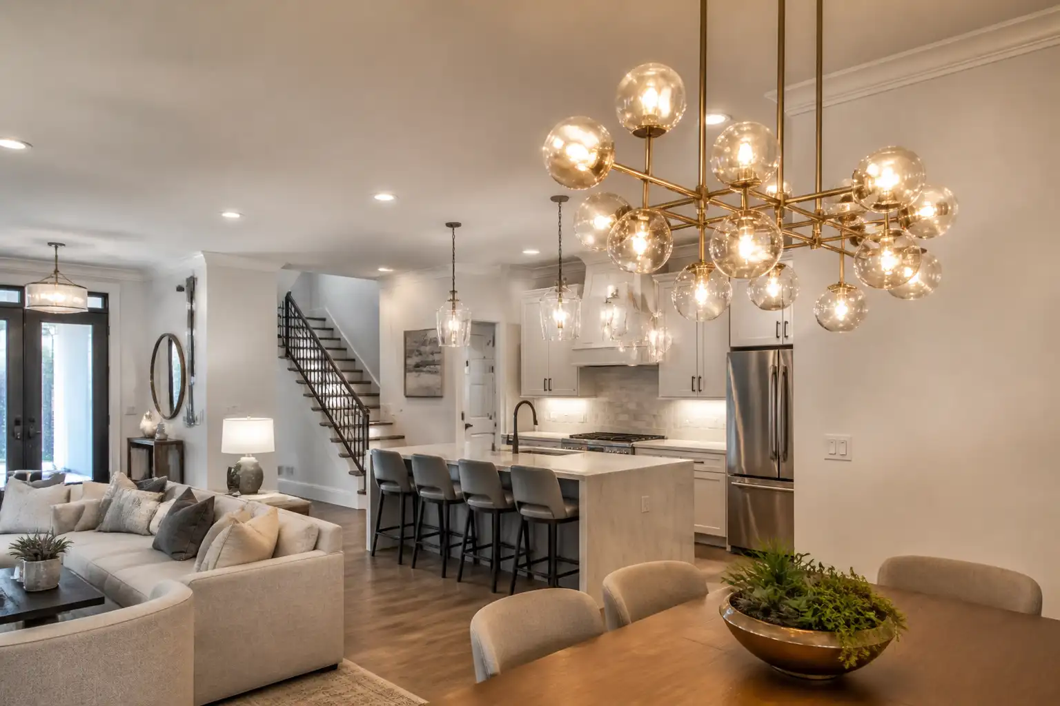 A bright kitchen with a center island, stools and a chandelier hanging above it